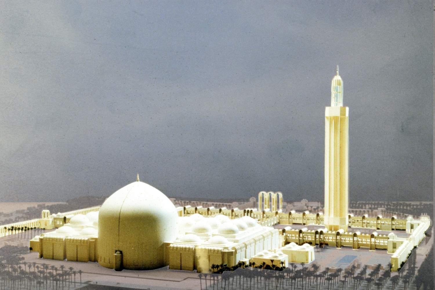 Baghdad State Mosque (Design) - <p>View of model with exterior of mihrab at the base of the main dome in foreground, to the multi-domed prayer hall, riwaq, boundary walls, minaret, and arches of the main entrance gate highlighted.</p>