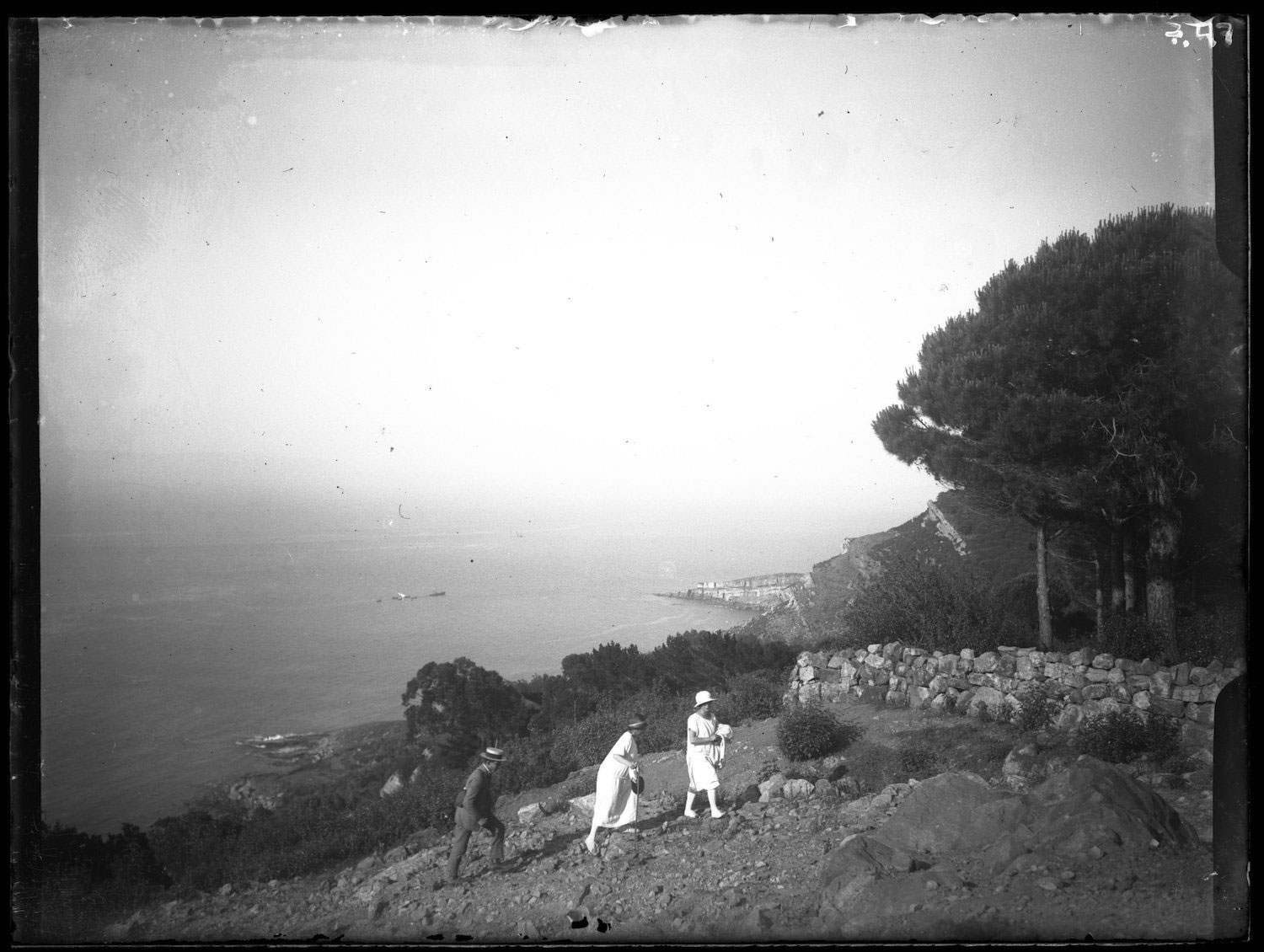 Europeans stand on a cliff overlooking the shore. 