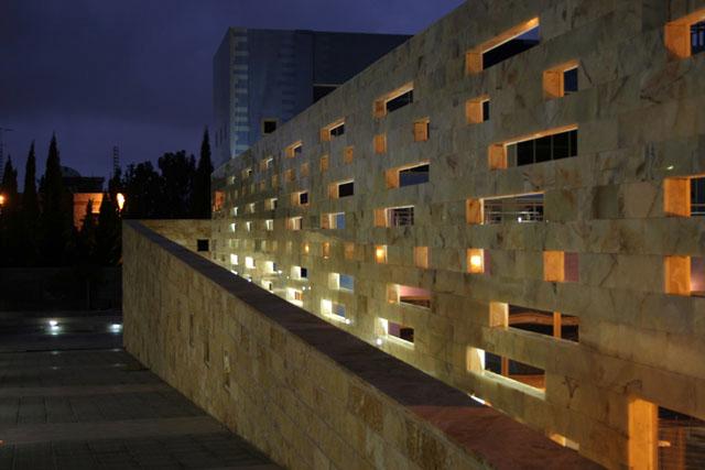 Night view of the walkway wall perforated with openings of irregular sizes and patterns