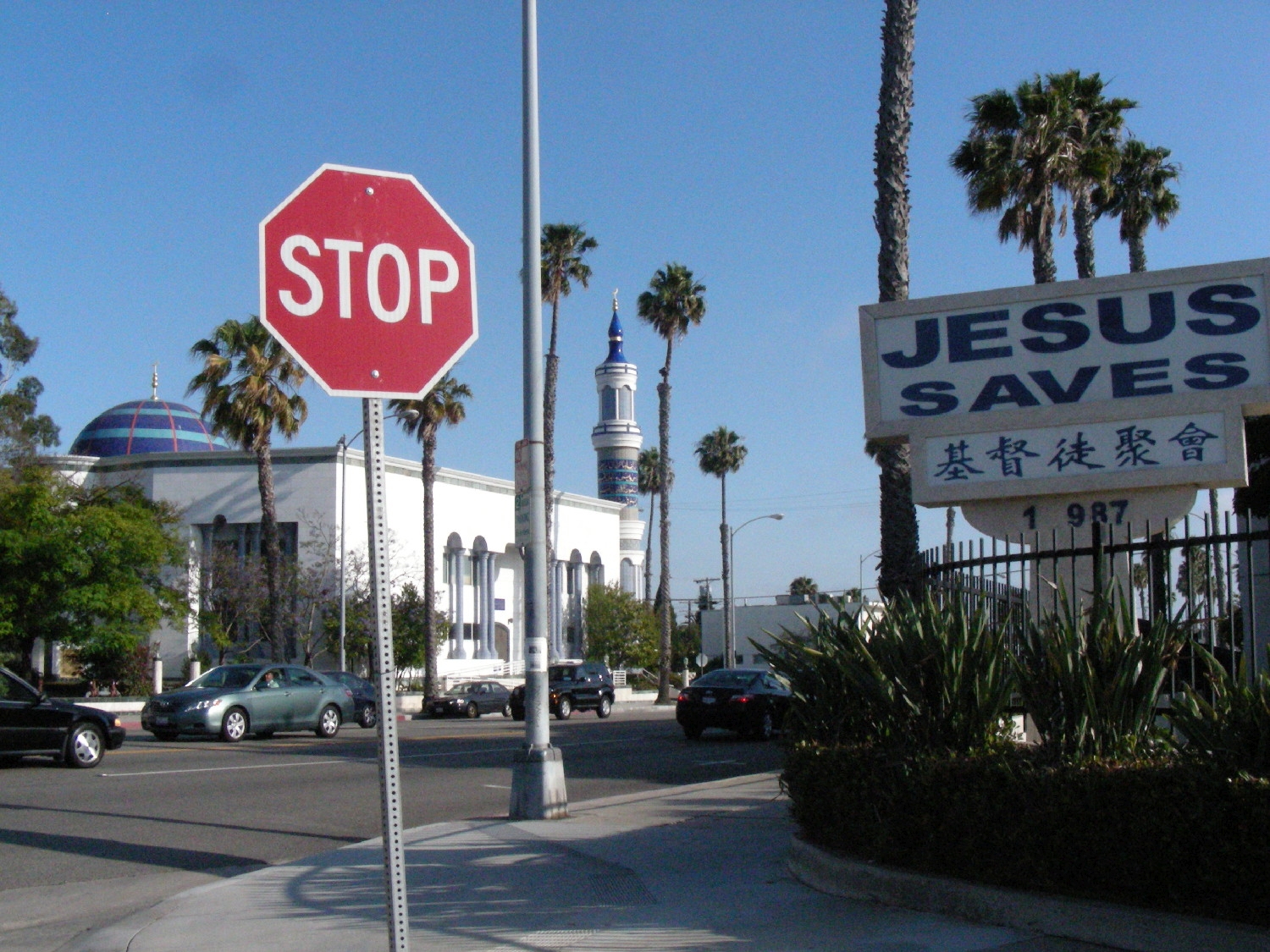 Mosque set in surrounding neighborhood, showing sign for church across the street "Jesus Saves"