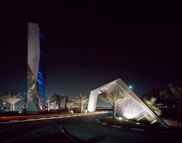 Illuminated steel and glass tower at main entry