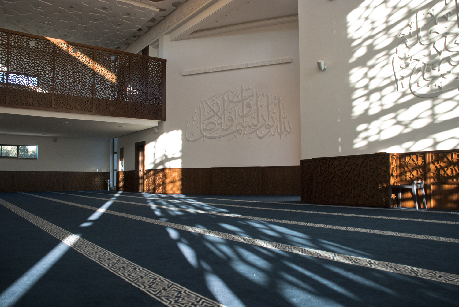 Morning sunlight penetrating the patterned freestanding façade into the prayer hall