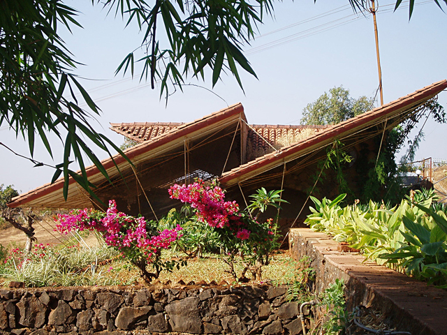 Exterior view of the garage showing the play of mangalore-tiled sloping roofs, supported by steel members on the ground