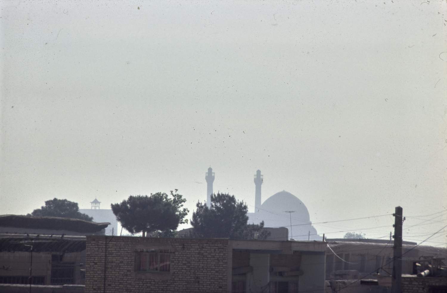 Distant view of dome and minarets from west over rooftops.