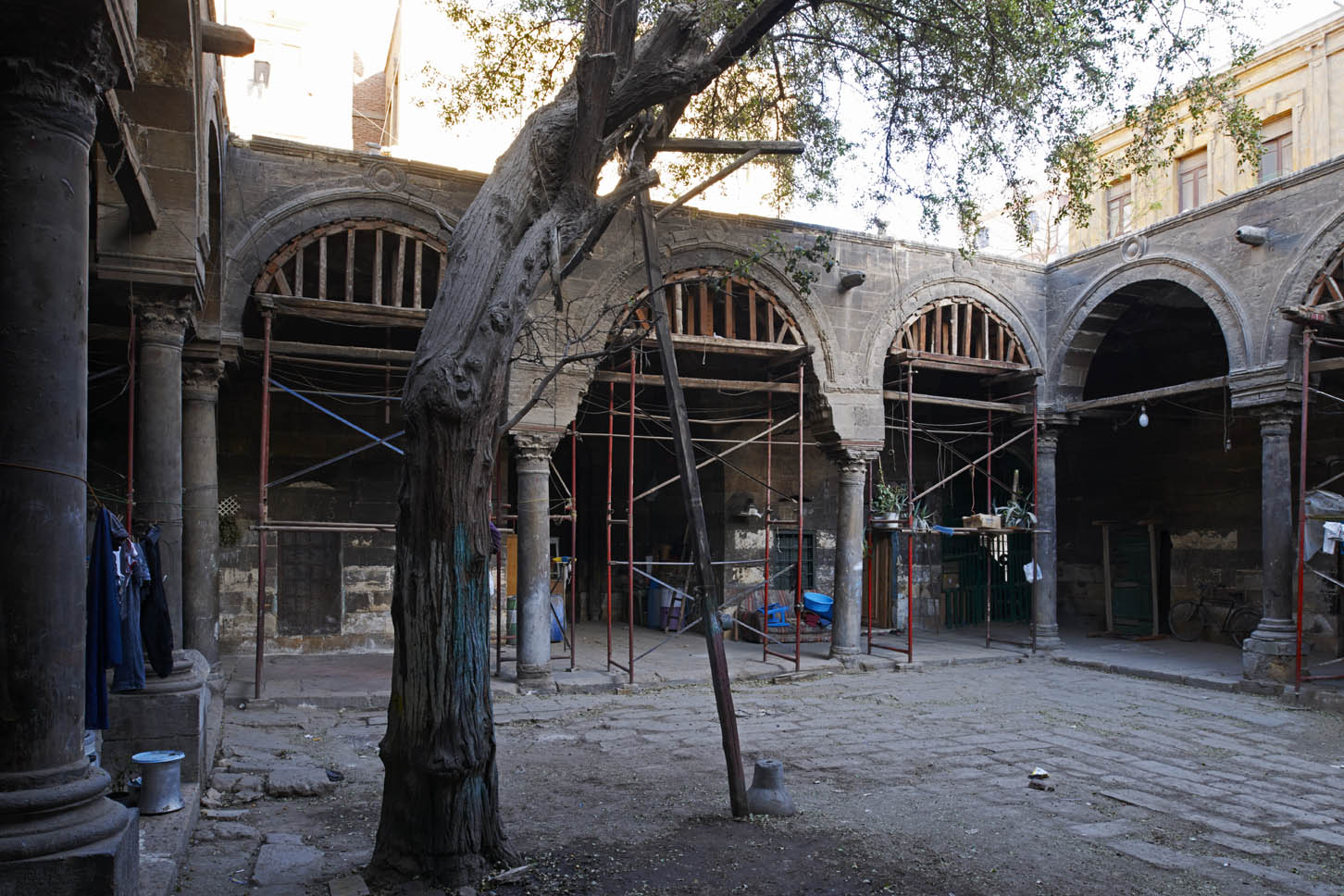 View within courtyard, with scaffolding in place in arches