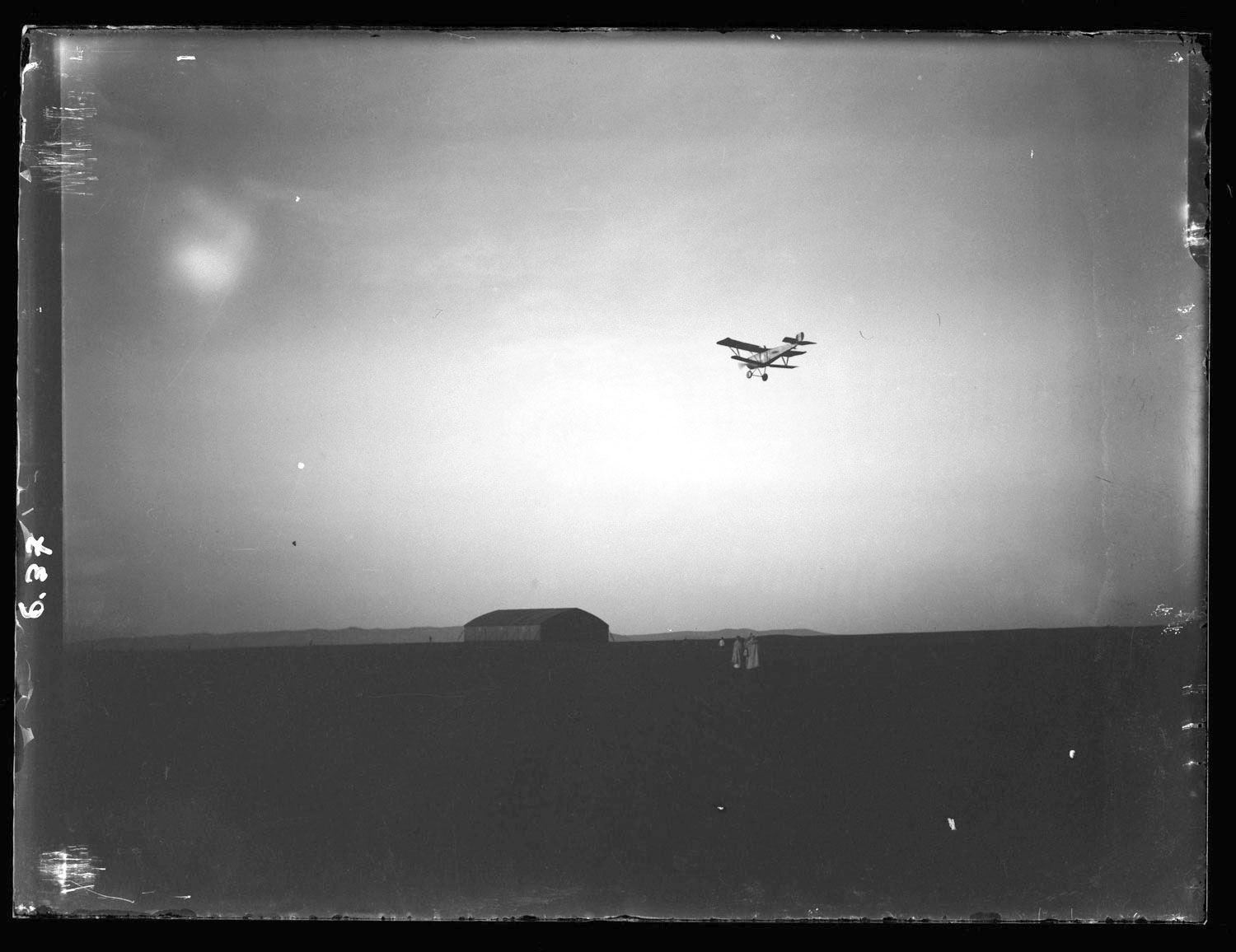 Aeroport Ibn Battouta de Tanger - Men stand on farm as a plane flies overhead.