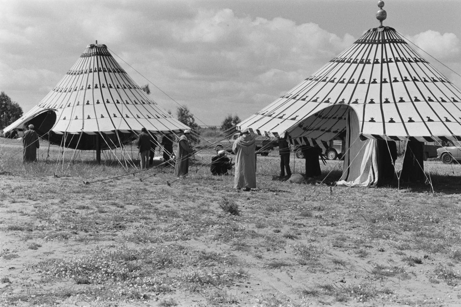 A group of men in traditional clothing setting up two celebration tents