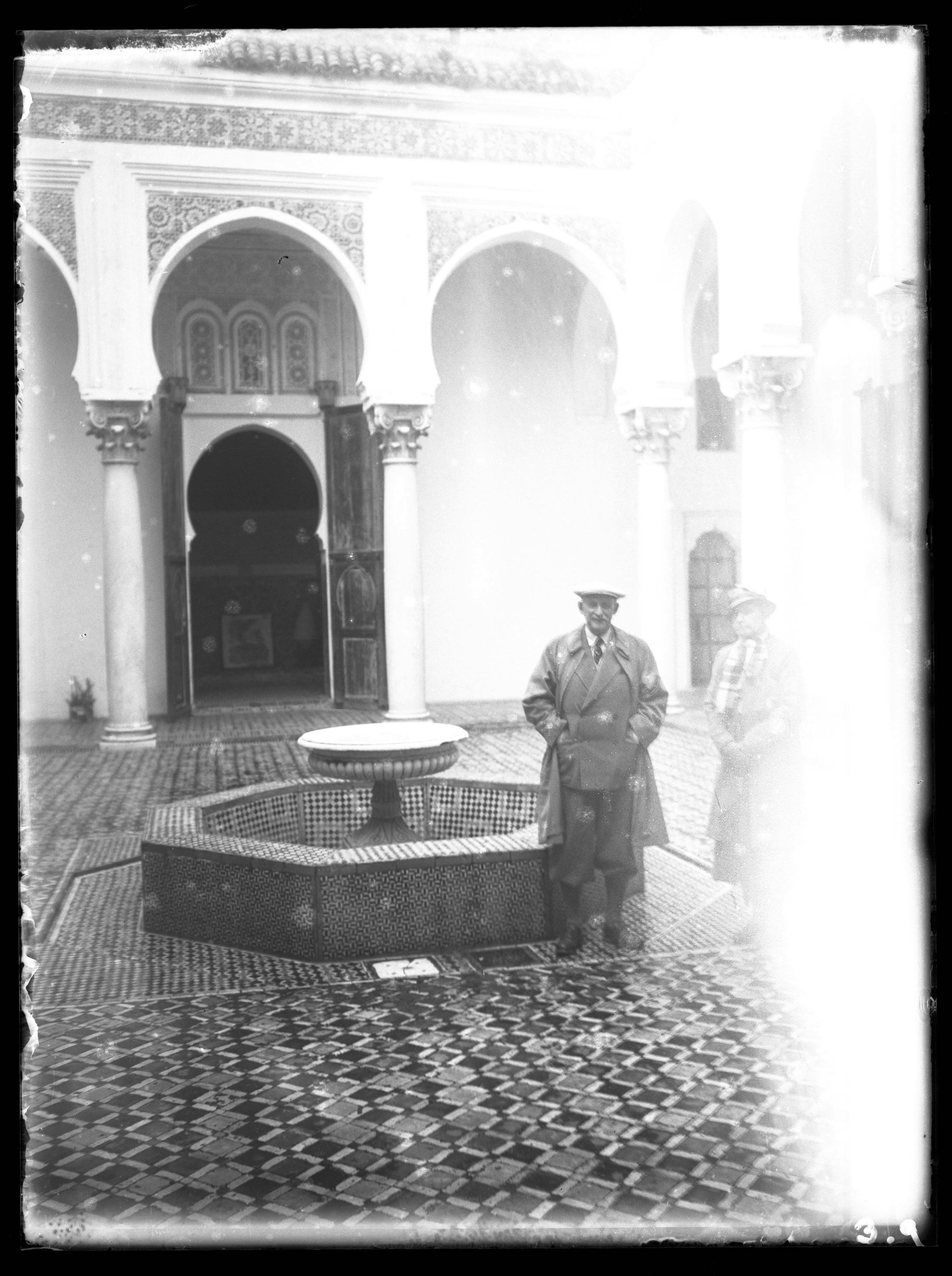 <p>Man and Woman in European dress pose next to a fountain in the courtyard.</p>