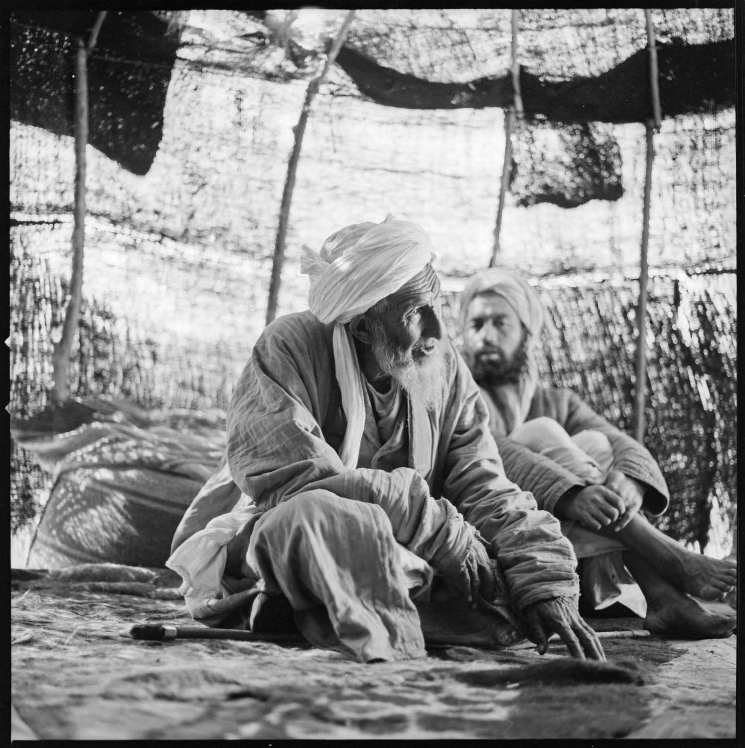 Men converse seated inside tent in the vicinity of Jam, Afghanistan.