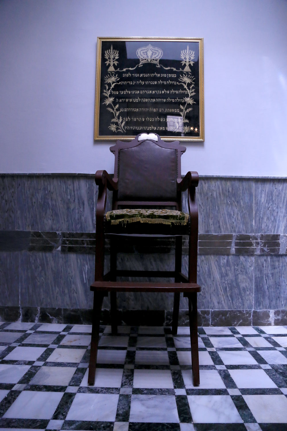 View of an elevated chair and framed tapestry