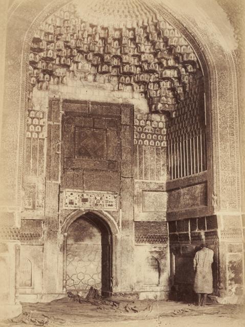 Interior view showing the arched niche on the qibla wall of the domed mosque with golden-edged muqarnas, prior to restoration