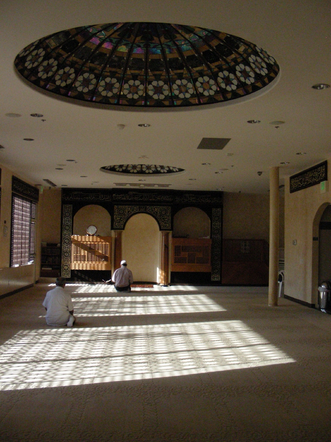 Prayer hall, view towards qibla wall. Patterned shadows from lattice windows visible on carpet