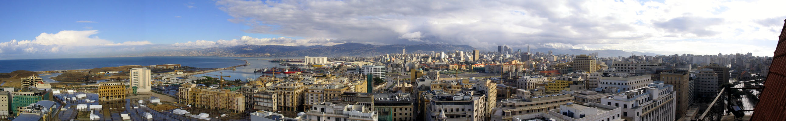 Panoramic view from north to south taken from the St. Louis clock tower, with Beirut's harbor and wheat silos seen on the left and the tall buildings of the Ashrafieh neighborhood on the right. The Kesrouan and Metn mountains are seen in the background