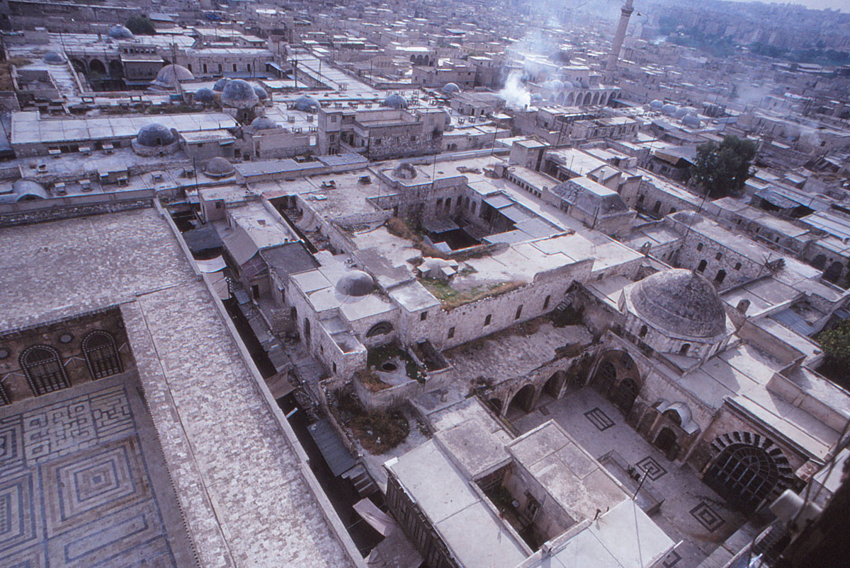 Madrasa al-Halawiyya - Aerial view over Madrasa al-Halawiyya and surrounding areas to south and west, taken from the minaret of Jami' al-Umawi. The corner of the mosque's courtyard is visible at left, and the courtyard of the madrasa visible in lower right.
