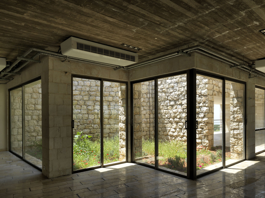 View from the inside to the entrance courtyard. The architect’s aesthetic of leaving exposed rough-cast concrete walls, gives the construction technology a structurally expressive role in the architecture and points to the handcraft culture in Jordan used to produce it

