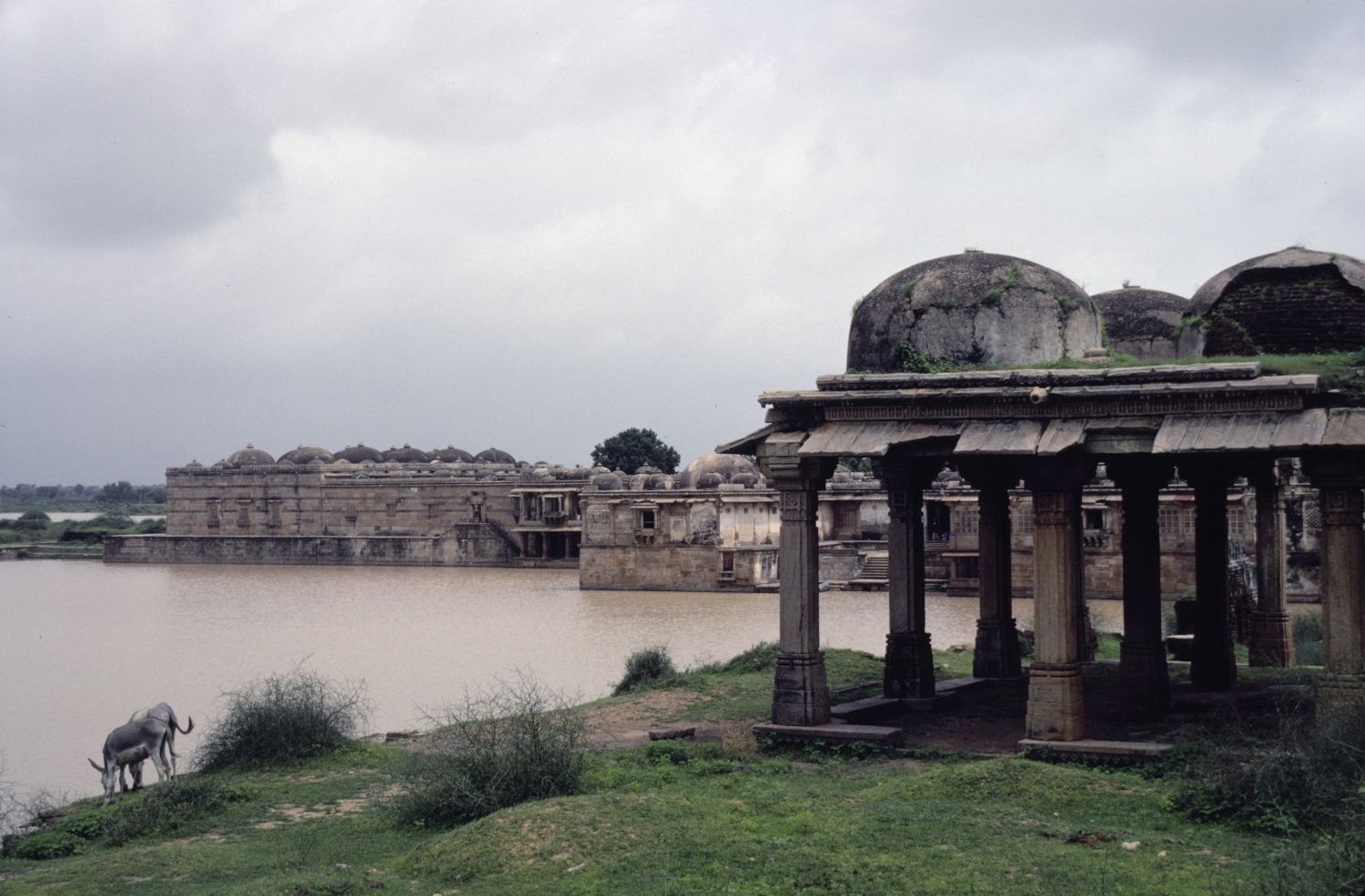 View from east bank of tank across the water facing northwest, with southern facade of mosque and tombs visible in background.