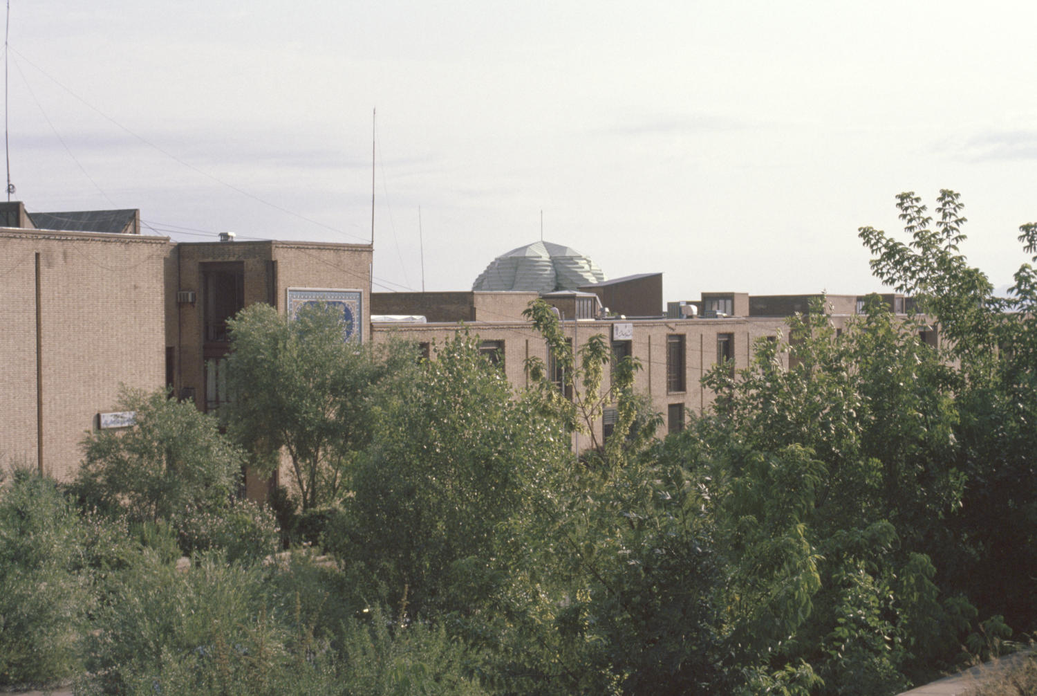 Bu-Ali Sina University - View of campus buildings seen over line of trees.