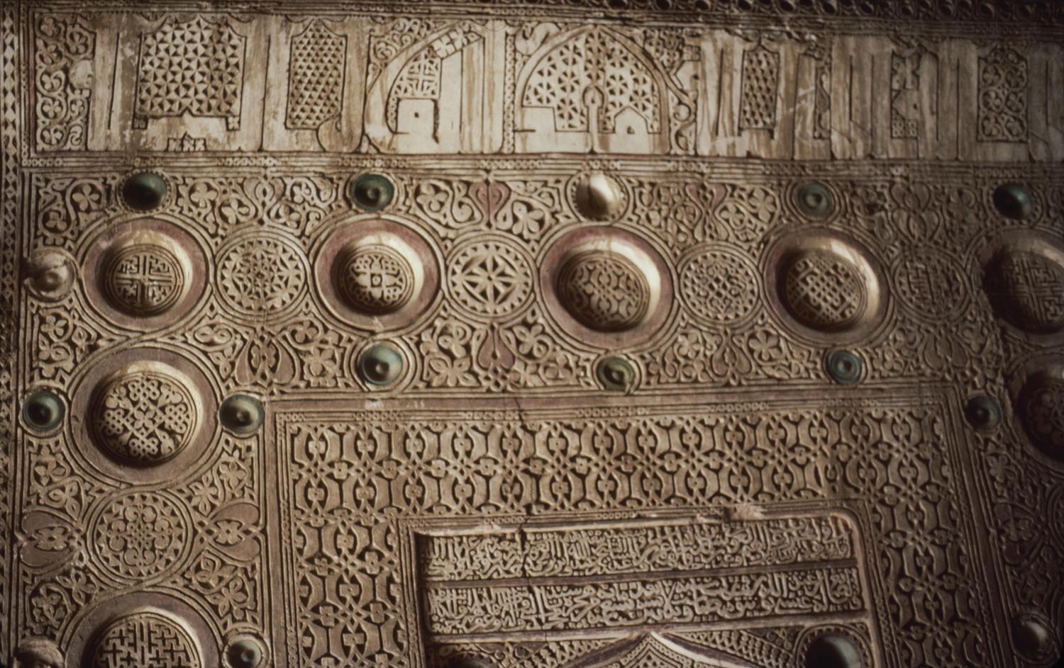 Detail of mihrab showing carved stucco work and inscription on frame.