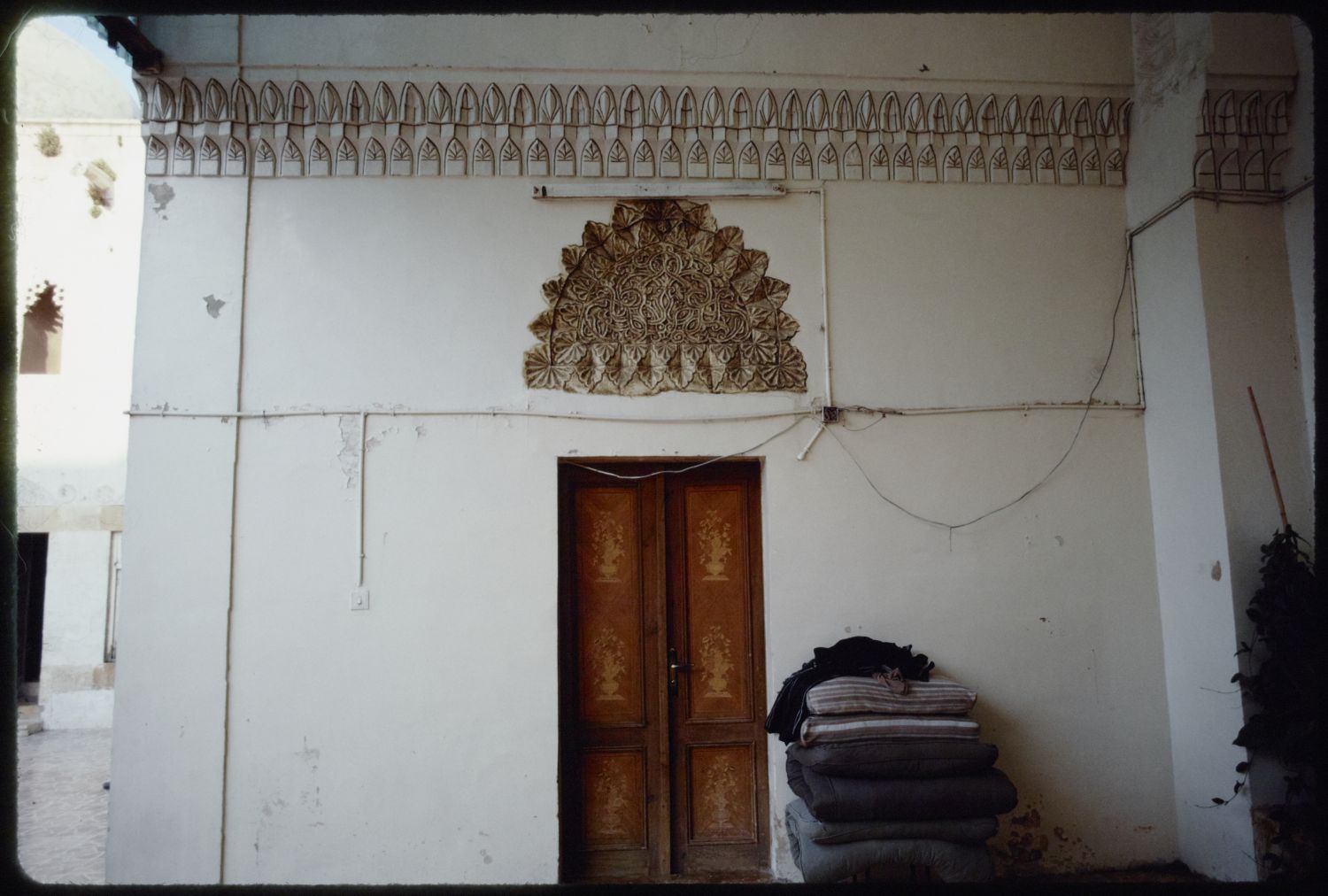 Interior of iwan, showing wall with decorative lunette and cornice.