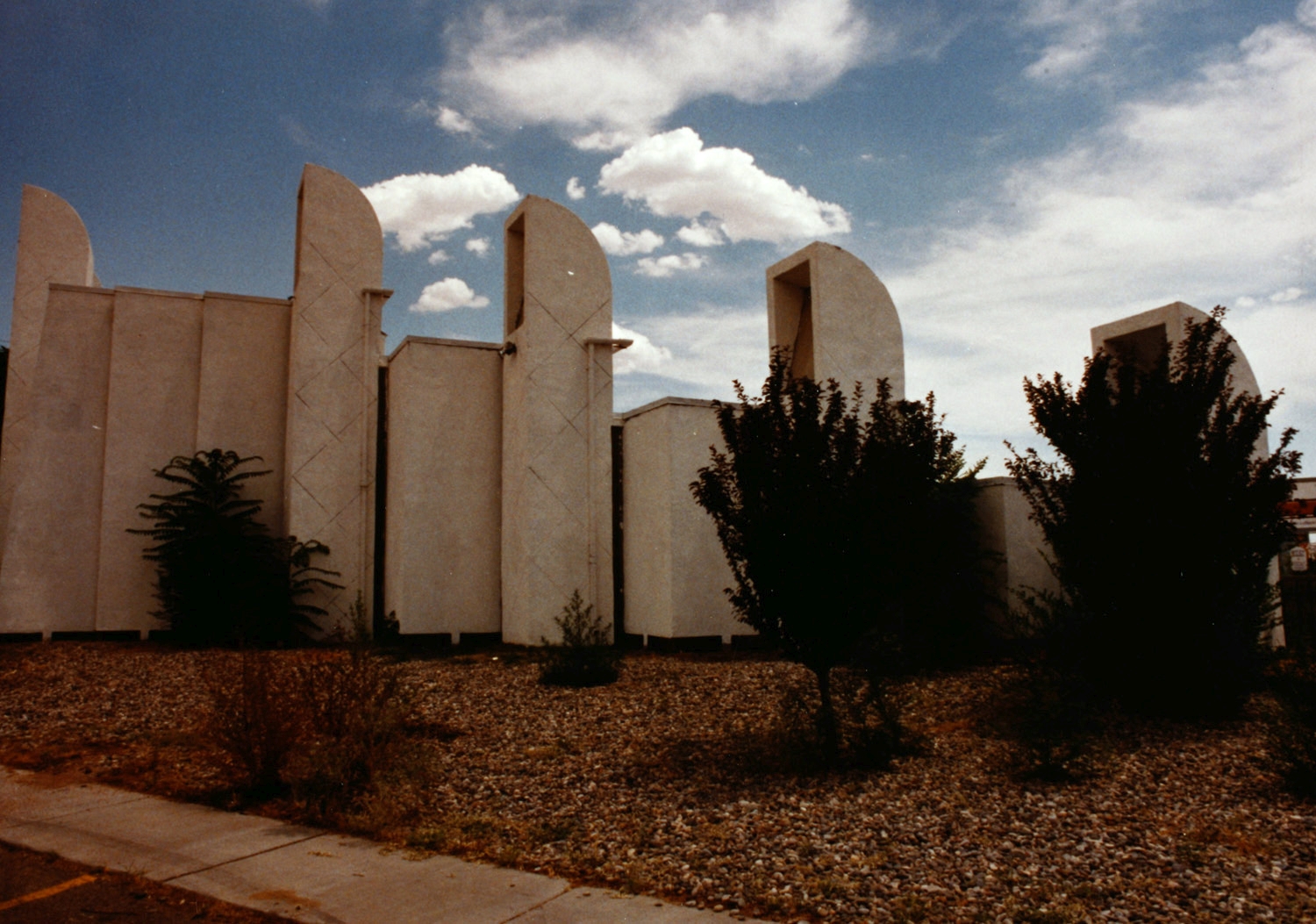 Exterior view, showing concrete facade and towers prior to painting