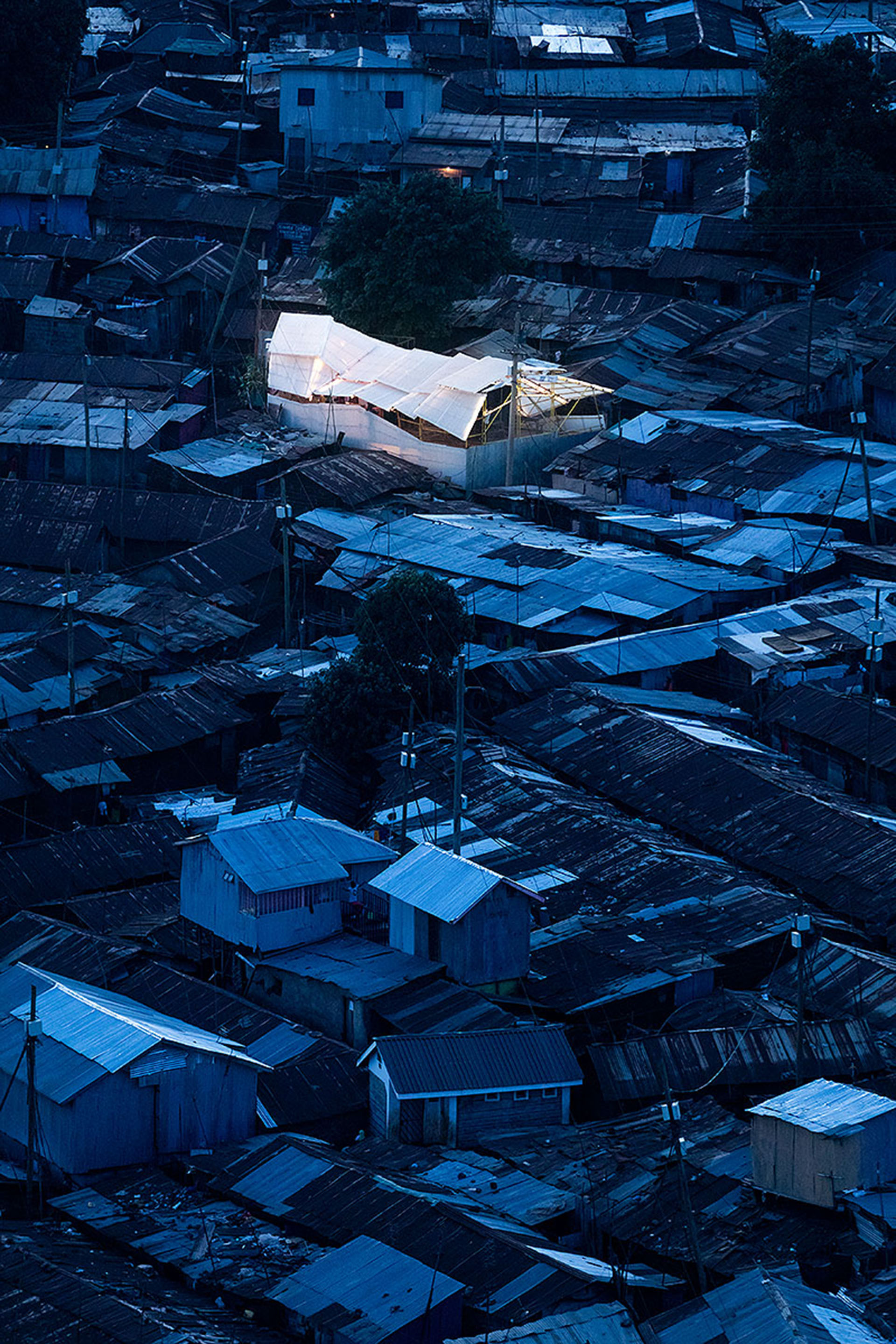<p>Aerial view. Walls and roofing are corrugated metal panels and thick plastic sheeting that, like the elements of metal scaffolding, are readily available throughout Africa.</p>