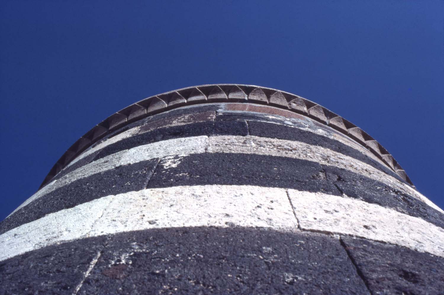 Detail view of minaret, showing use of alternating colors of stone on shaft and stone carving on cornice.