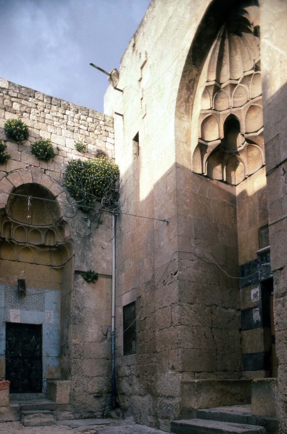 Close view of entrance portals, with small north portal to residential unit at left and larger entrance portal to madrasa at right.
