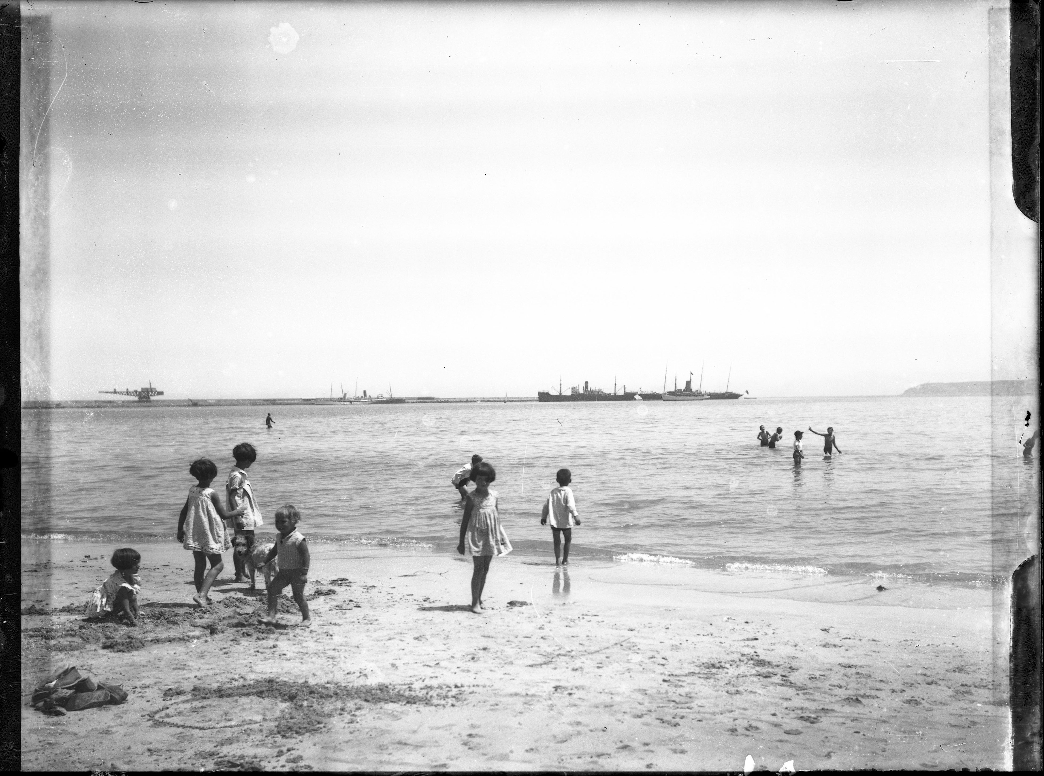 <p>Children play on the beach near the port</p>