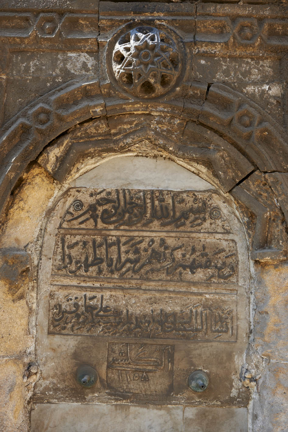Detail of drinking spout with marble inscription flanking entrance portal