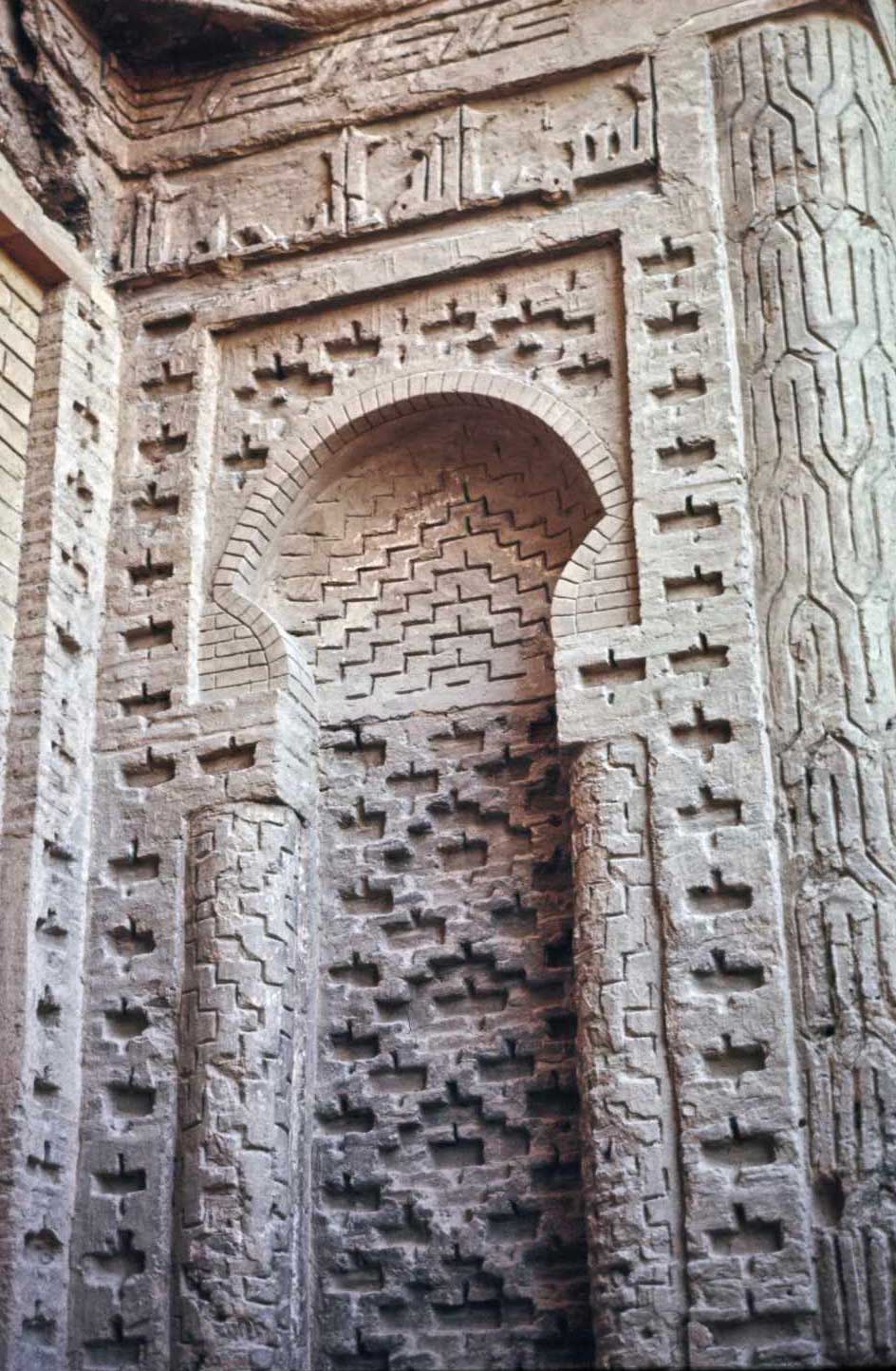 Detail view of a decorative brick recess with inscriptions niche flanking main portal. 