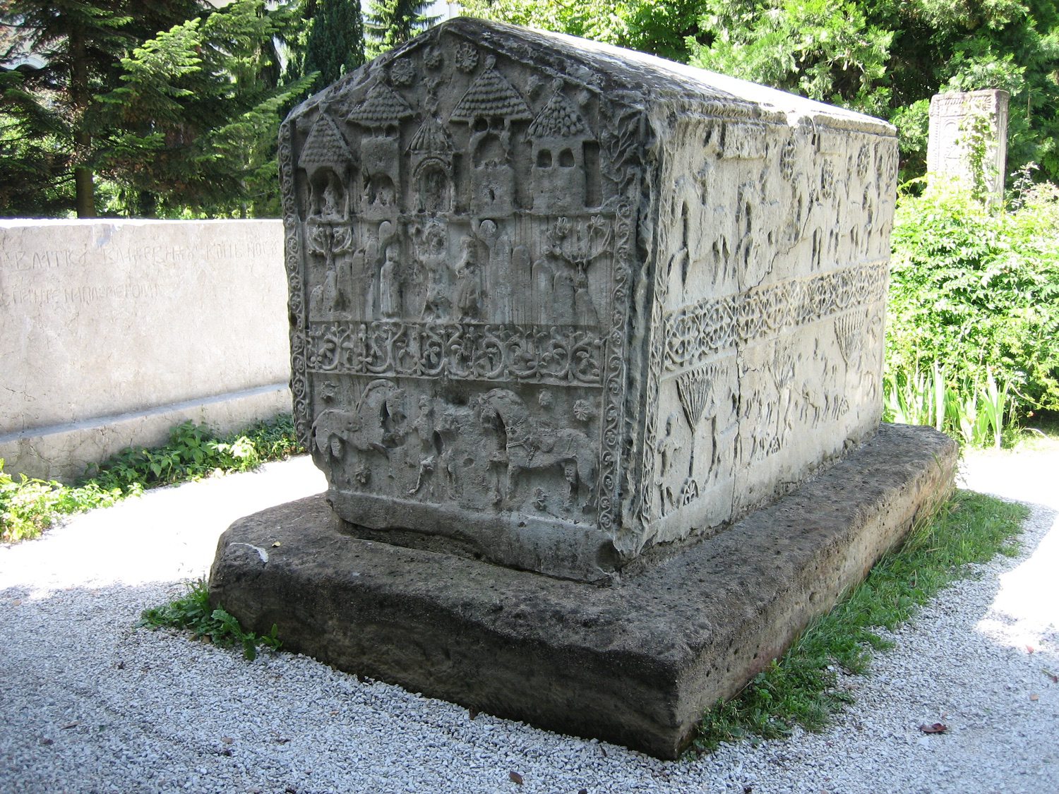 <p>This stećak is an important tombstone of the region. Scholars contend that it was made during the 14th century and served as the tombstone of the medieval Bosnian King Stjepan II who died in 1353. The illustrations of buildings on the end are believed to be some of the earliest representations of Bosnian domestic structures. The stećak was found in Donja Zgošća near Kakanj, approximately 50 kilometers north of Sarajevo along the Bosna River. The tombstone now sits in the garden of the Bosnia and Herzegovina National Museum in Sarajevo.&nbsp;</p>