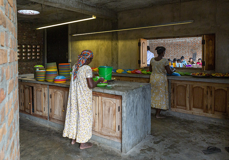 <p>Women prepare the children's meals in a kitchen adjacent to the cafeteria.</p>
