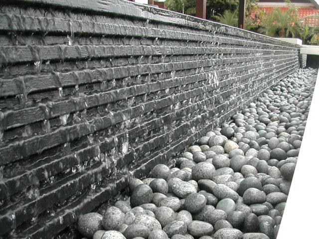 The water cascades down a 60 mm high black slate onto edges of smooth river pebbles
