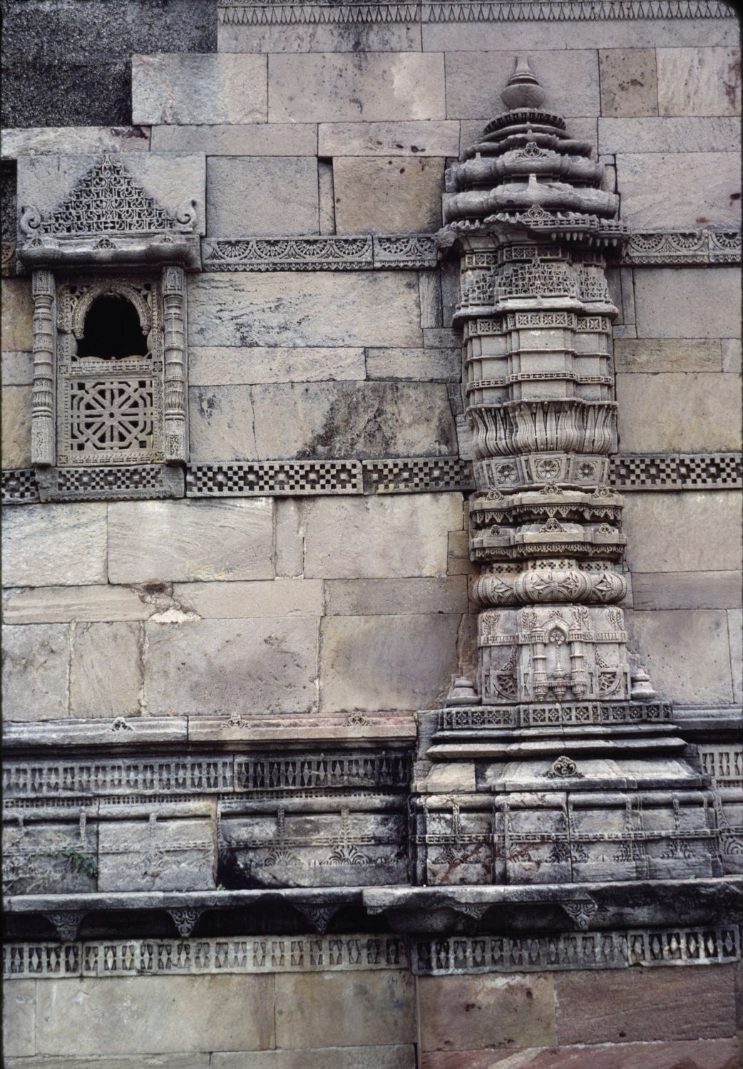 Exterior view of western (qibla) wall showing an ornate carved buttress and small window.