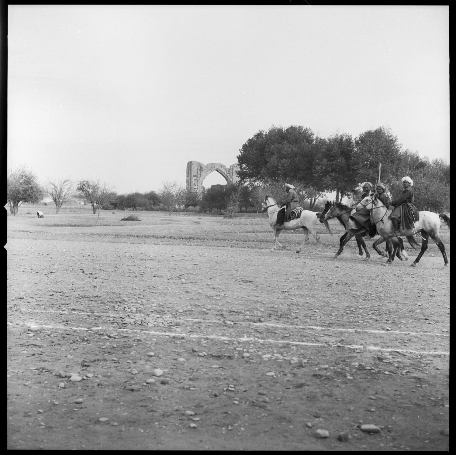General distant view with men on horses passing in foreground.