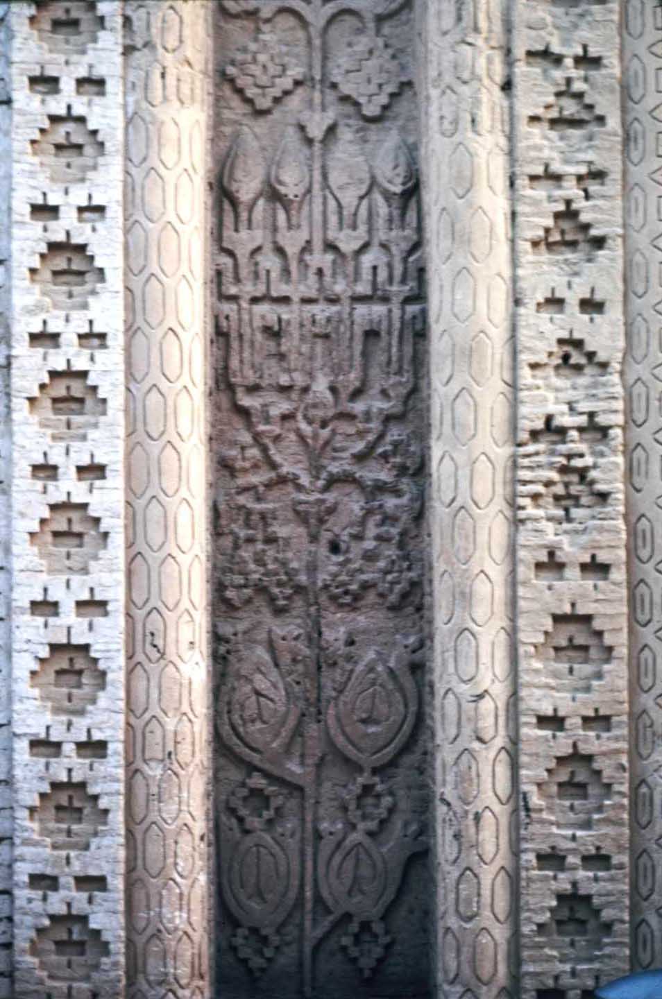 <p>Detail view of a decorative recess with stylized, vegetal patterns, flanked by geometric brickwork</p>