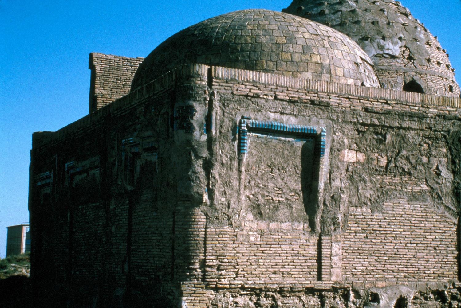 Exterior view from the northwest, with the intact dome of the Shrine of Sayf al-Din Bakharzi in the background