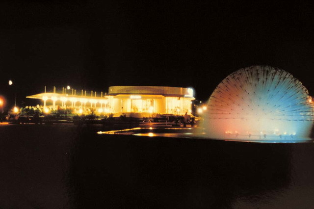 Exterior view at night, with sculpture in ornamental pool