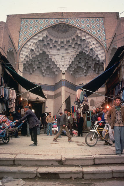 View of portal with muqarnas hood, with shops in the foreground