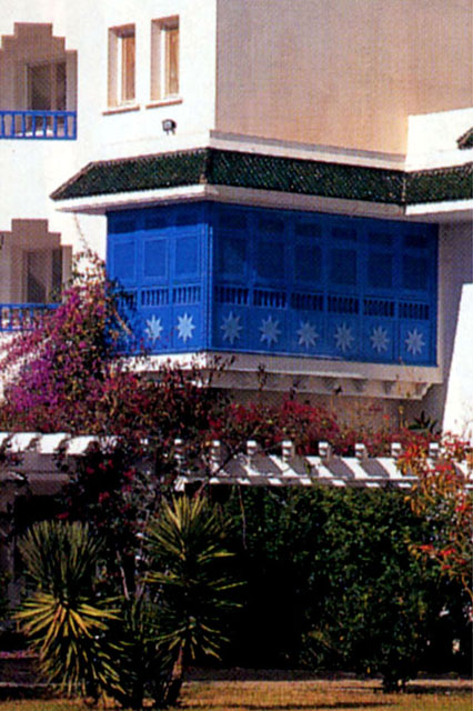 Exterior view showing white-washed façade and recessed mashrabiyya screens