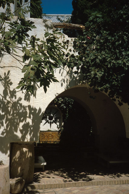 Exterior view showing arched entrance swathed in foliage