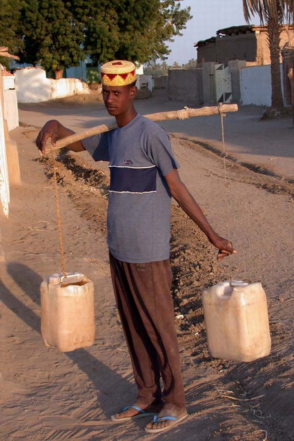 Man carrying water by hand before the water project