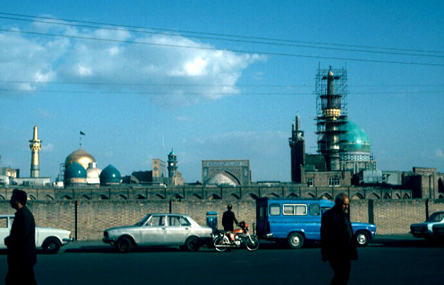 Street view from the west, with the blue dome of the Gawhar Shad Mosque and the gold sanctuary dome