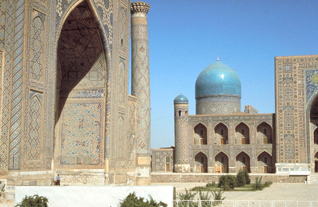 View within the square toward the northwest. The pishtaq and northern minaret of the Ulugh Beg madrasah stand on the left. The Tilla Kari madrasah is on the right