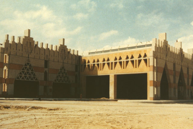 Exterior view showing wall with alternating stone patterns and irregular archways composed of jagged brick patterns