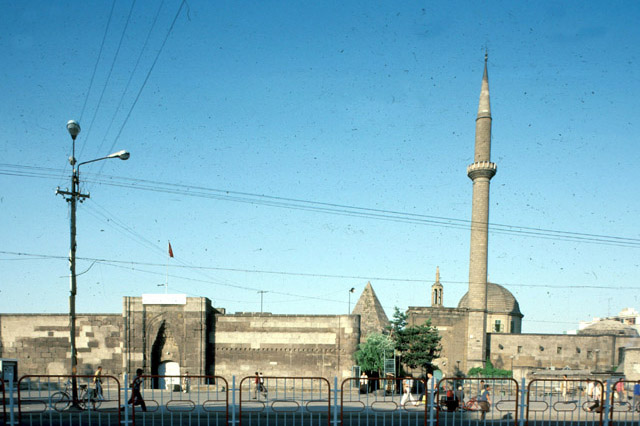 Exterior view from west-southwest, showing the madrasa entrance on the left, the conical dome of the tomb at center, and the mosque entrance and minaret on the right