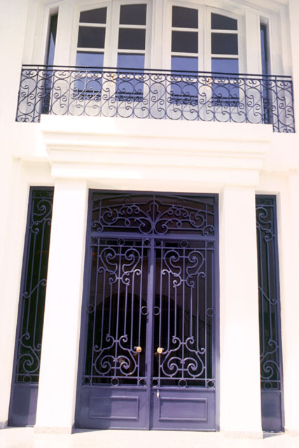 Exterior detail showing iron grate doors and upper level window and balcony