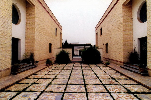 Exterior view, paved patio between houses with facing entrances
