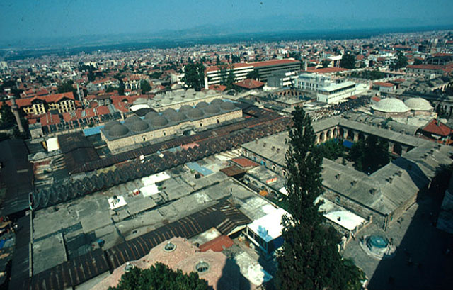 Aerial view of the old market neighborhood, as seen from the minaret of Ulu Cami.The domes of Sengül Hamami (now the jewelry market) and the roofs of the closed bazaar occupy the foreground flanked by Emir Han, Bey Hamami and Koza Han on the east. To the north are the fourteen domes of Bedesten with the domes of Sipahiler Carsisi in the background, with Geyve Han and Fidan Han visible to the east of Bedesten