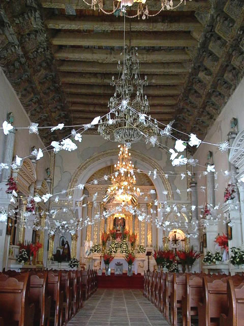 Interior view towards the altar, showing artesonado ceiling, bracketed cornice, and pews